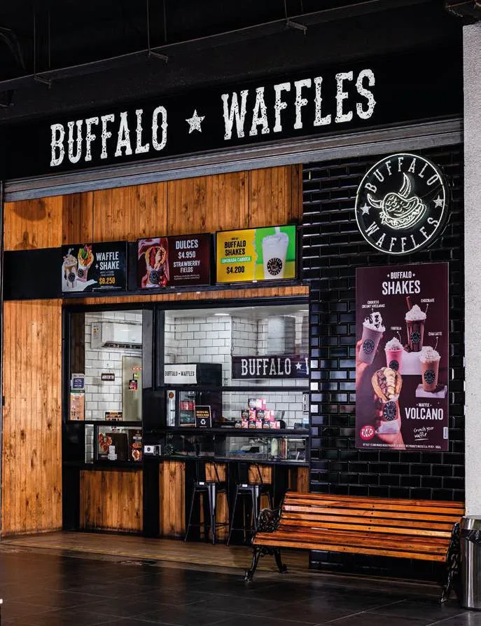 Local Buffalo Waffles dentro de un centro comercial, con muro de azulejos negros y el isologo de la marca